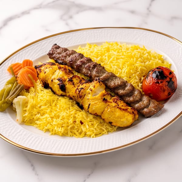 A plate of yellow rice with chicken and beef kebabs, a grilled tomato, and pickled vegetables.