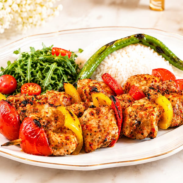 Chicken shish kebabs with bell peppers, rice, arugula salad, and a grilled green pepper.